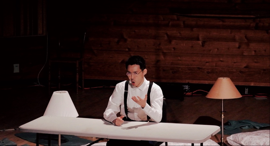 A person in suspenders and a microphoneDescription automatically generated