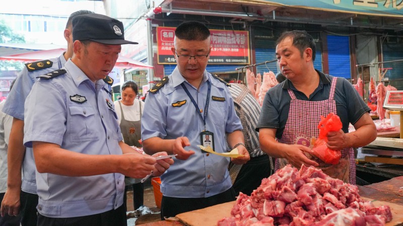 1787891137919317.jpg 2执法人员在肉制品销售摊位检查相关票据。.jpg